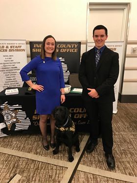 Rachel Striks and Eric Nesbitt standing in front of the Ingham County Sheriff's Office booth at the 2019 Criminal Justice Career Fair